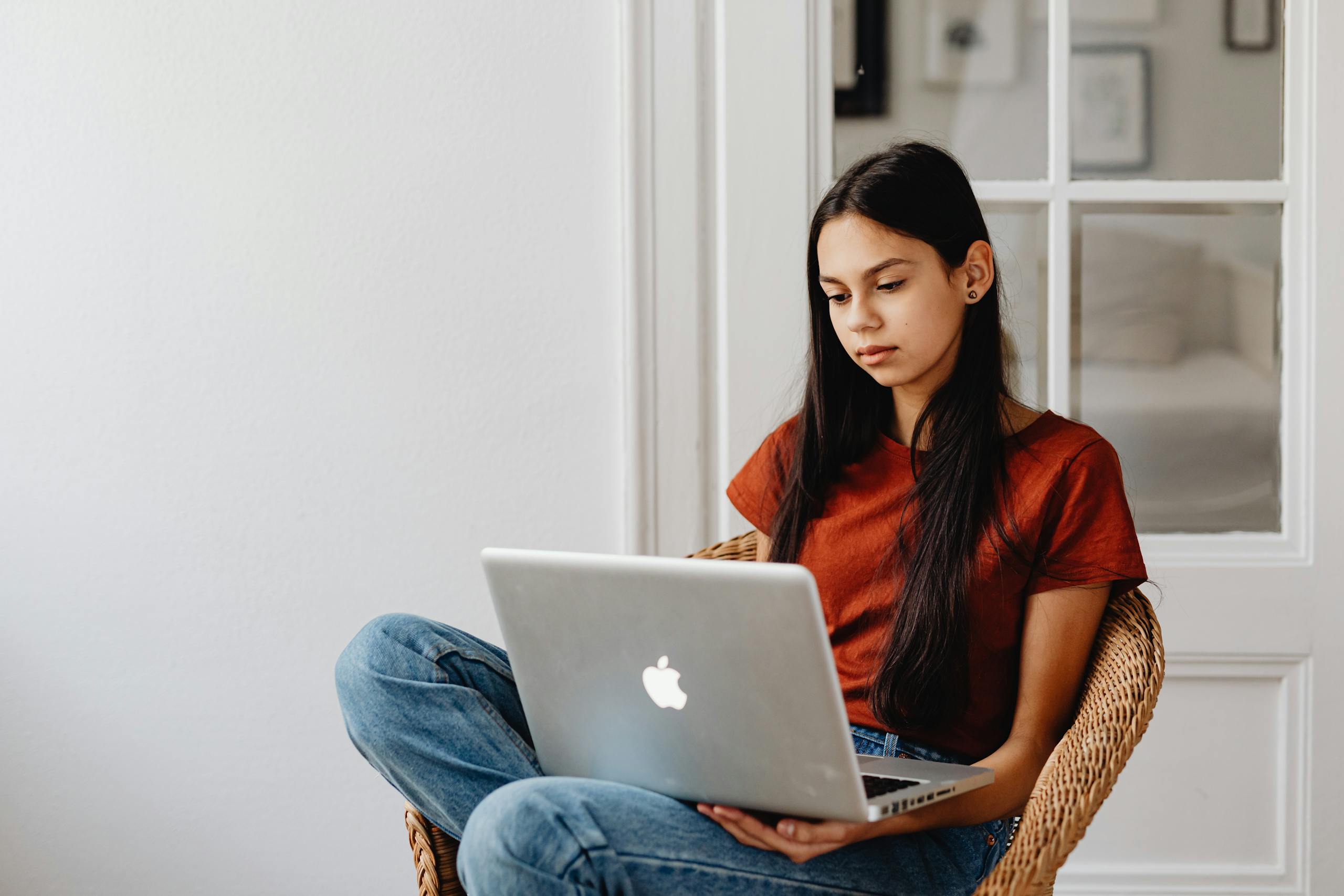 A teenage girl sits comfortably while using a laptop indoors during trauma therapy