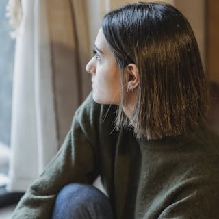 Thoughtful young woman gazing out a window, exuding serenity and contemplation.